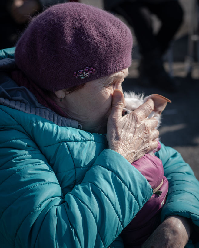 An elderly Ukrainian refugee kisses her dog.