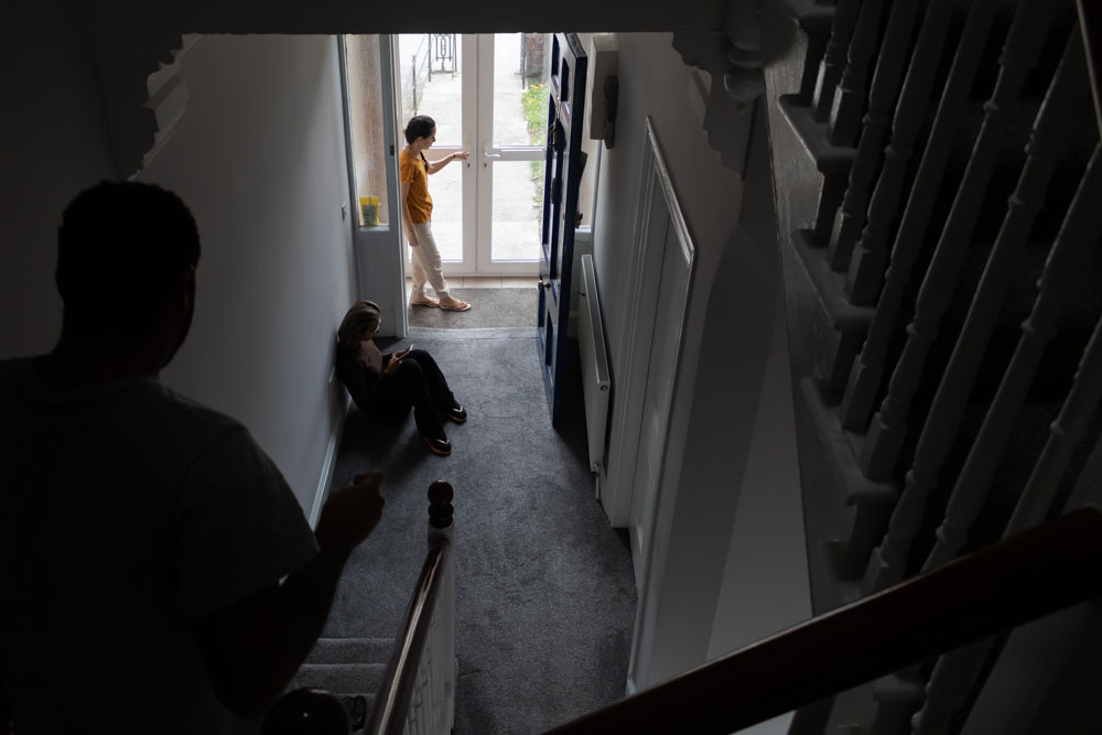 From left to right: Jonathan going downstairs, Carla sitting on the ground doing English lessons on her phone, and Jéssica at the door, coming back from taking the trash out. As the house didn’t have many common areas, the residents would often study or work sitting on the hallway floor.